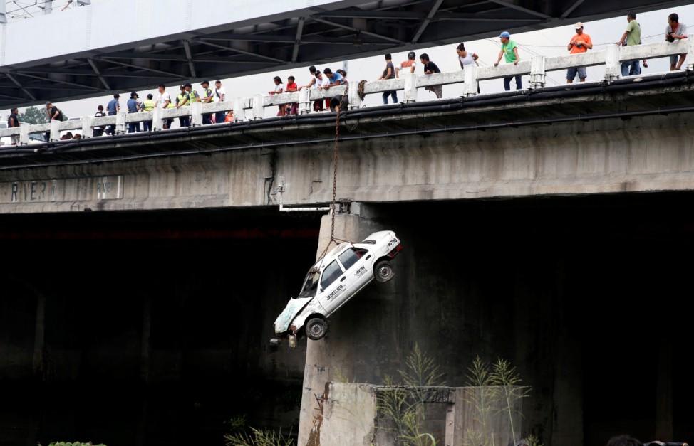 A taxi hangs beside a bridge to simulate an earthquake aftermath, during a metrowide earthquake drill along main highway EDSA in Makati, Metro Manila