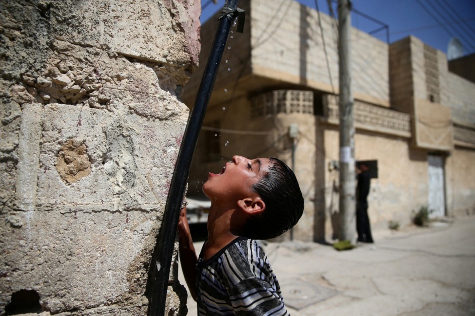 A boy drinks water from a pipe, in the rebel held besieged town of Douma, eastern Damascus suburb of Ghouta