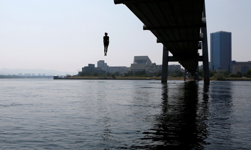 A man jumps from a 12-metre-high footbridge into the waters of the Yenisei river on a hot summer day in the Siberian city of Krasnoyarsk