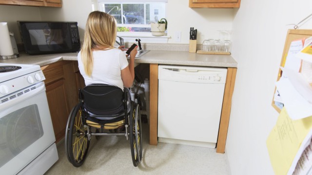 Woman with spinal cord injury in kitchen MODEL RELEASED Woman with spinal cord injury in her access