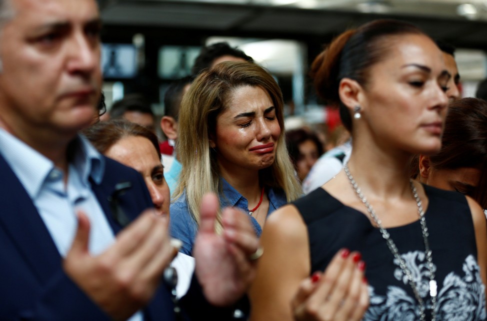 Airport employees mourn for their colleagues, who were killed in Tuesday's attack at the airport, during a ceremony at the international departure terminal of Ataturk airport in Istanbul