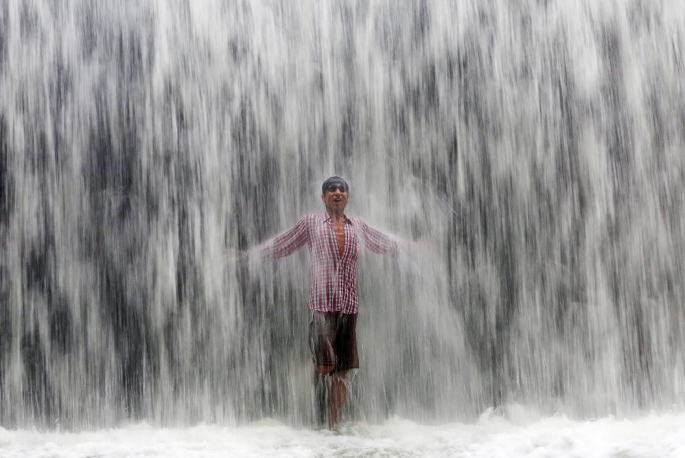 A boy stands under an overflowing dam along the Powai lake after heavy rains in Mumbai