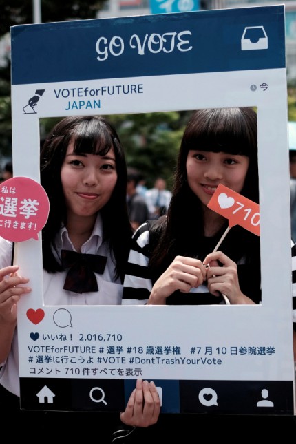 High school students pose for photos with a cardboard Instagram frame calling on youths to vote in the July 10 upper house election, in Tokyo