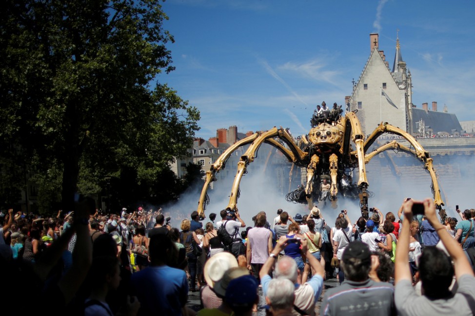 People look at the giant mechanical spider Kumo Ni created by La Machine production company during its presentation in Nantes
