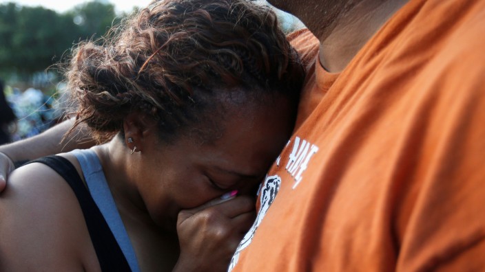 Victor Taylor supports Keaka Wallace who says she was a patrol partner of slain DART officer Brent Thompson, weeps as she leaves a makeshift memorial at Dallas Police Headquarters following the multiple police shooting in Dallas