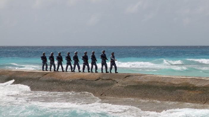 Soldiers of China's People's Liberation Army (PLA) Navy patrol near a sign in the Spratly Islands, known in China as the Nansha Islands