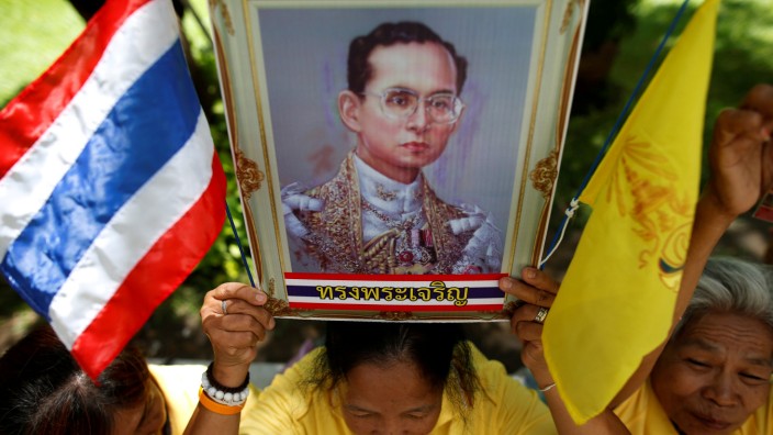 A well-wisher holds a picture of Thailand's King Bhumibol Adulyadej at the Siriraj hospital where he is residing, in Bangkok
