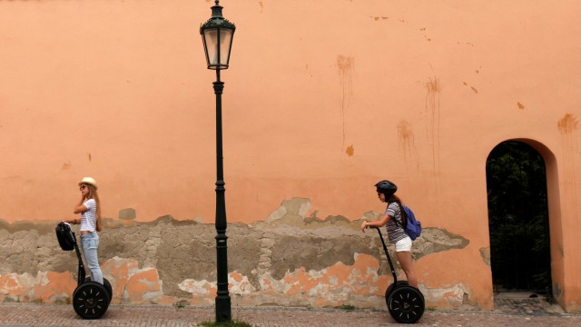 Tourists ride on Segways through a street in central Prague