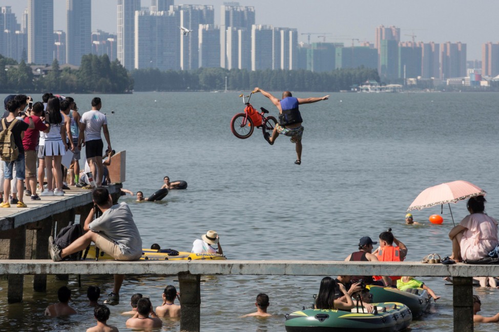 A participant jumps into a lake with a bike during a local event to call on residents to protect environment in Wuhan