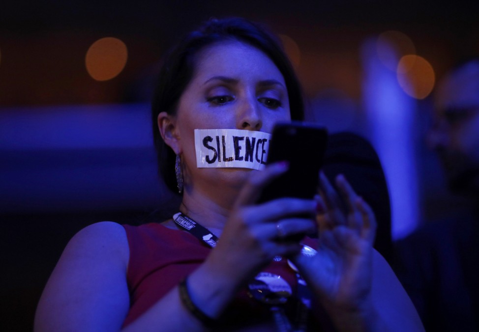 A delegate with tape covering her mouth in protest looks at her smartphone at the Democratic National Convention in Philadelphia