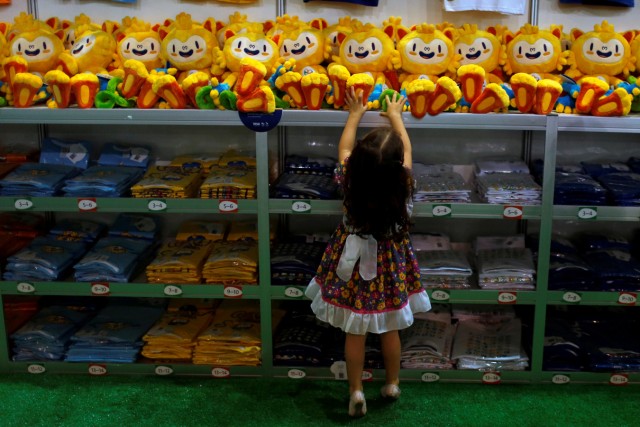 A child tries to reach a Rio 2016 Olympic mascot Vinicius doll during the opening of the Olympics megastore on Copacabana beach in Rio de Janeiro