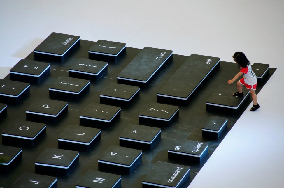 A child climbs onto a giant mockup laptop keyboard during a promotion event at a shopping centre in Beijing