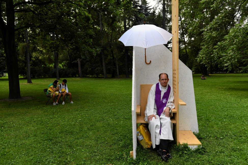 A priest waits for faithful in a confessional before a mass led by Pope Francis in Krakow