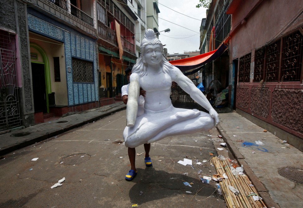 An artisan carries an idol of Hindu god Shiva to a workshop through an alley in Kolkata