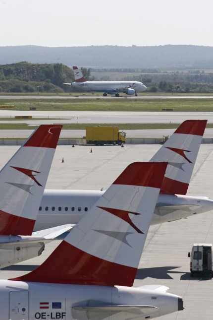 An Austrian Airlines plane taxis along the runway for take-off behind parked planes at the airport in Vienna