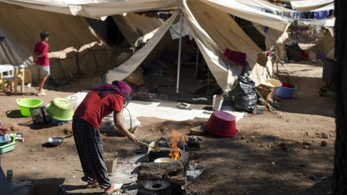 Folgen des EU-Türkei-Deals: Eine syrische Frau kocht in einem Flüchtlingslager nördlich von Athen: Tausende sitzen in Griechenland fest.