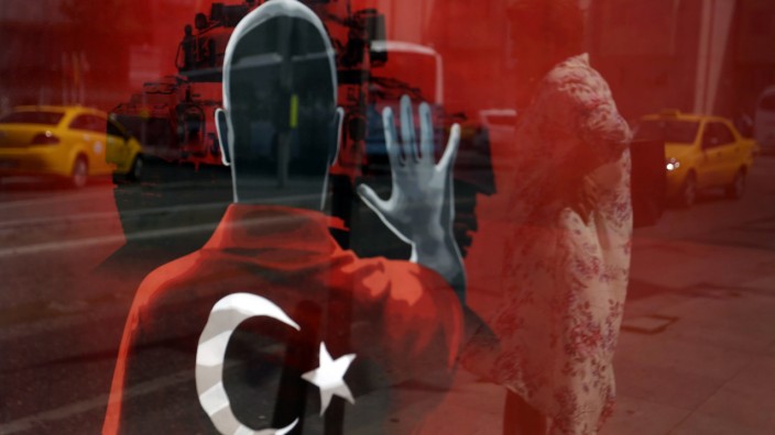 Türkisches Tagebuch (XIX): Martialische Bildsprache: Eine Frau spiegelt sich in einem Propagandaplakat der Regierung in Istanbul. Gegen Andersdenkende wird hart durchgegriffen.