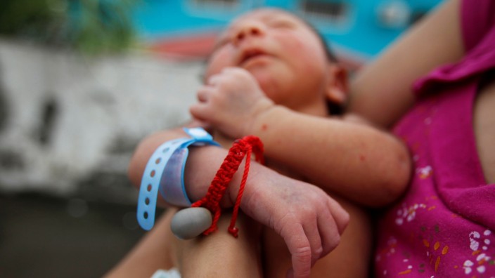 Melissa holds her nine-day old baby Allan, who was born with microcephaly and who wears a good-luck charm, while standing on the roof top of their home in Choluteca