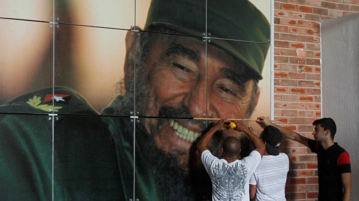Workers install a photograph of Cuba's former president Fidel Castro at the Expocuba exhibition center in preparation for his upcoming 90th birthday in Havana