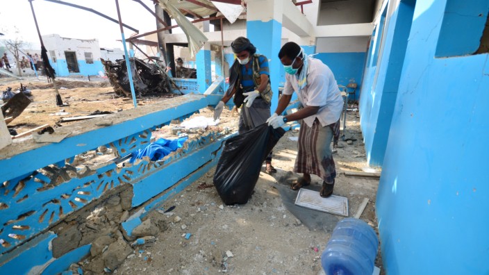 Workers collect human remains at the yard of a hospital operated by Medecins Sans Frontieres after it was hit by a Saudi-led coalition air strike in the Abs district of Hajja province, Yemen