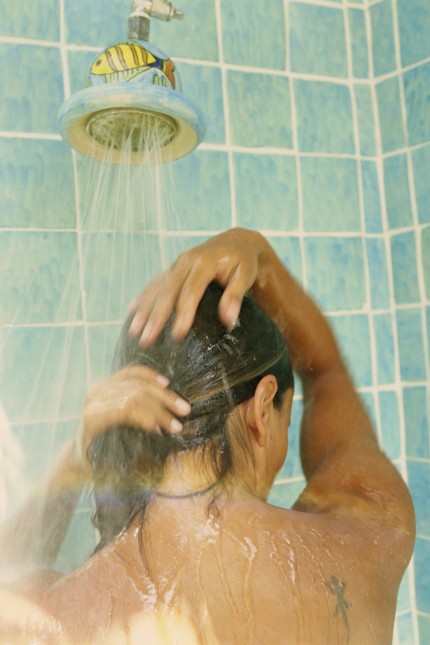 Young woman showering, close-up, rear view