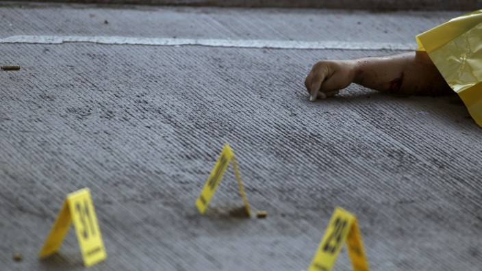 Evidence markers are seen next to a slain body at a crime scene in Tegucigalpa