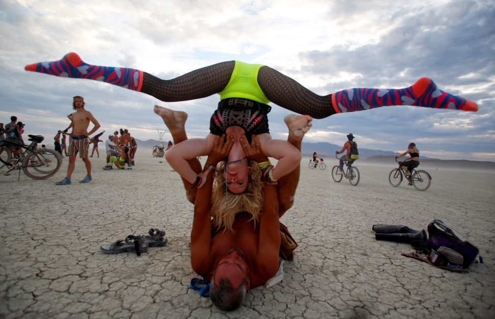 Mark Dill and Brit Thacker practice acro-yoga as approximately 70,000 people from all over the world gather for the 30th annual Burning Man arts and music festival in the Black Rock Desert of Nevada