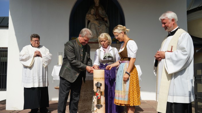 Wiesn-Kerze: Georg und Renate Heide, Tochter Daniela Heide und Pater Matthäus beim Entzünden der Kerze.