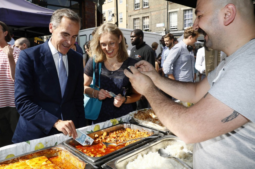 Bank of England governor Carney tests a new polymer five pound note as he buys lunch at Whitecross Street Market in London