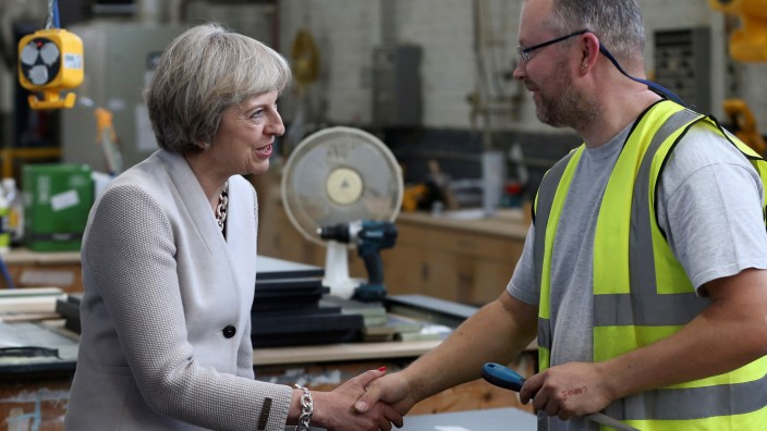 Britain's Prime Minister Theresa May speaks with a worker as she visits a joinery factory in London