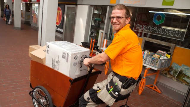 Dorfladen Olympiawerk, Olympiadorf. Sie fangen im Oktober einen ganz neuen Service an, bei dem sie mit E-Lastenrädern Pakete im autofreien Olympiadorf ausliefern.