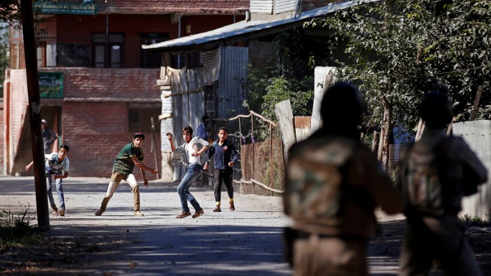 Youths hurl stones towards the Indian police during a protest against the recent killings in Kashmir, in Srinagar