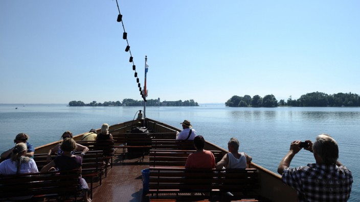 Touristen fahren mit einem Ausflugsschiff auf dem Chiemsee (Bayern) auf die Fraueninsel (l) und die unbewohnten Krautinsel zu