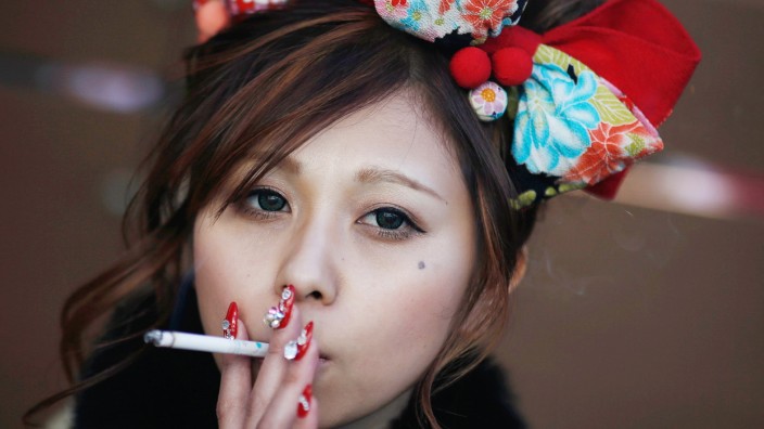 Mitomi holds a cigarette after a Coming of Age Day celebration ceremony at an amusement park in Tokyo