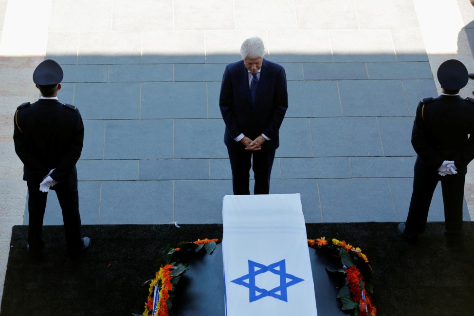 Former U.S. President Bill Clinton stands next to the flag-draped coffin of former Israeli President Shimon Peres, as he lies in state at the Knesset plaza, the Israeli parliament, in Jerusalem