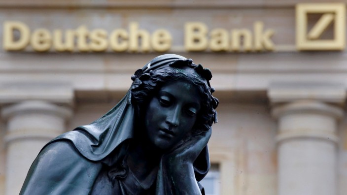 A statue is seen next to the logo of Germany's Deutsche Bank in Frankfurt