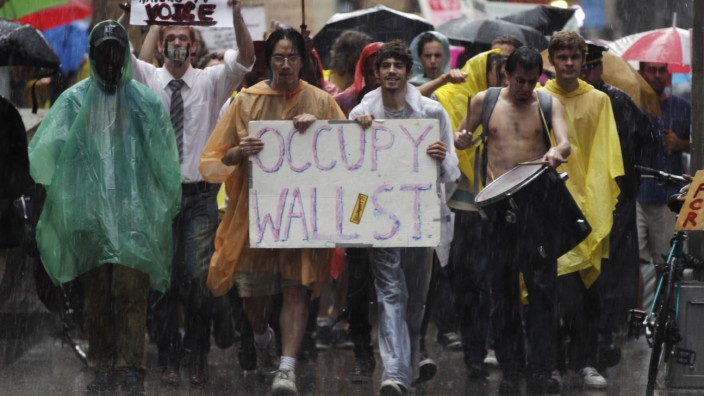 Demonstrators from the Occupy Wall Street campaign march in the rain through the streets of the financial district of New York