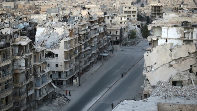 People walk past damaged buildings in the rebel-held Tariq al-Bab neighbourhood of Aleppo