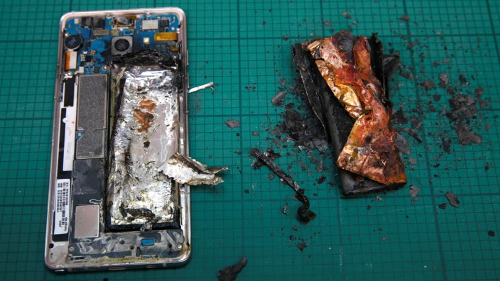 A Samsung Note 7 handset is pictured next to its charred battery after catching fire during a test at the Applied Energy Hub battery laboratory in Singapore
