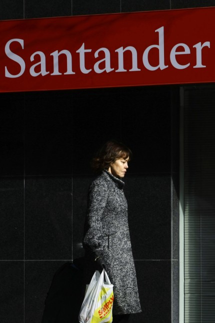 Woman walks past Santander bank branch in central Madrid