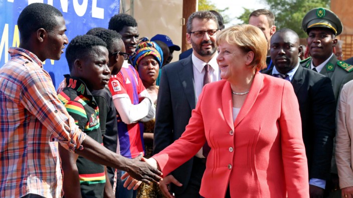 German chancellor Angela Merkel greets men at an International Organization for Migration transit center in Niamey