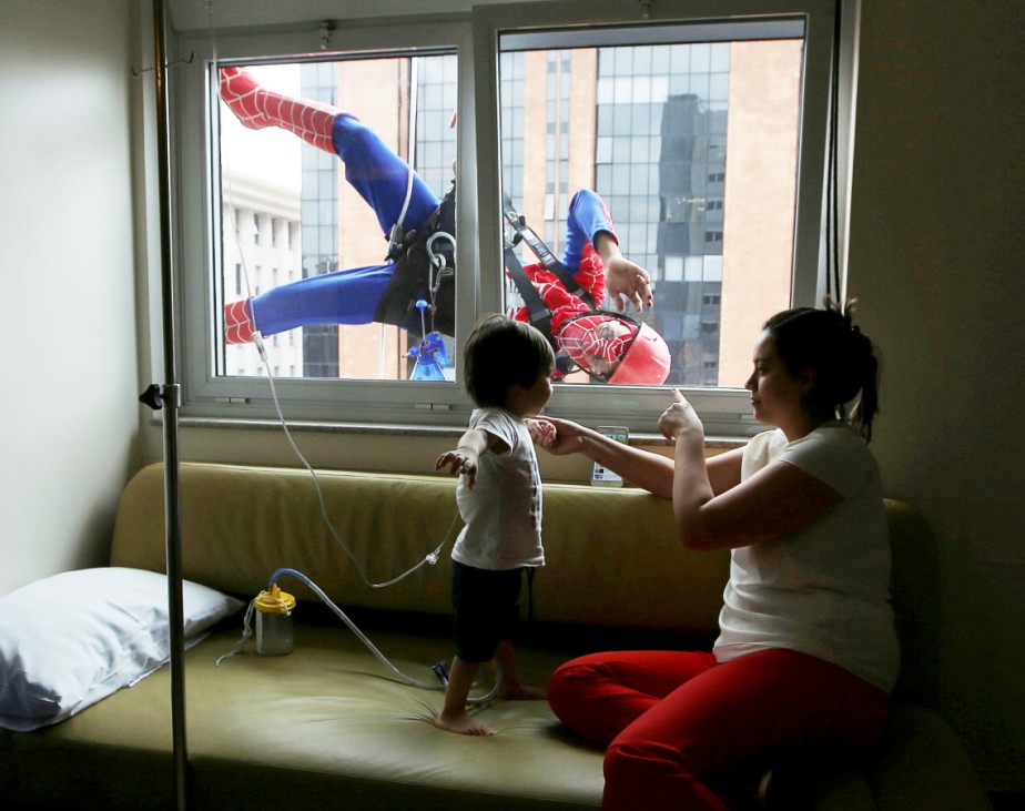 Men dressed as Spiderman jokes with patient Lucas, and his mother, looking on inside Hospital Infantil Sabara in Sao Paulo