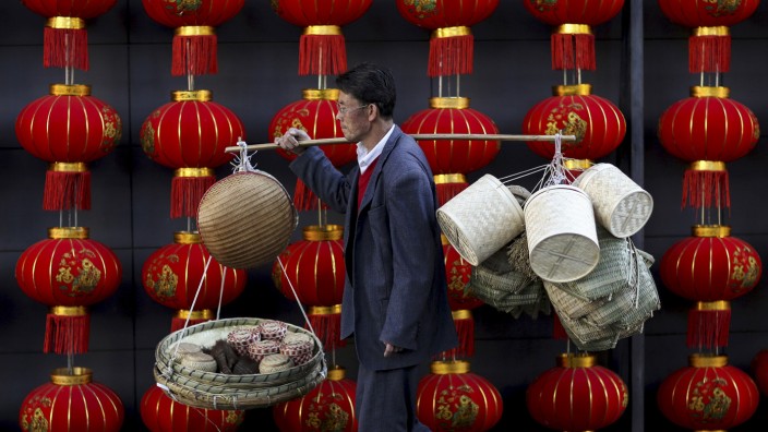 File photo of a basket vendor walking past red lanterns serving as decorations to celebrate the new year outside a shopping mall in Kunming