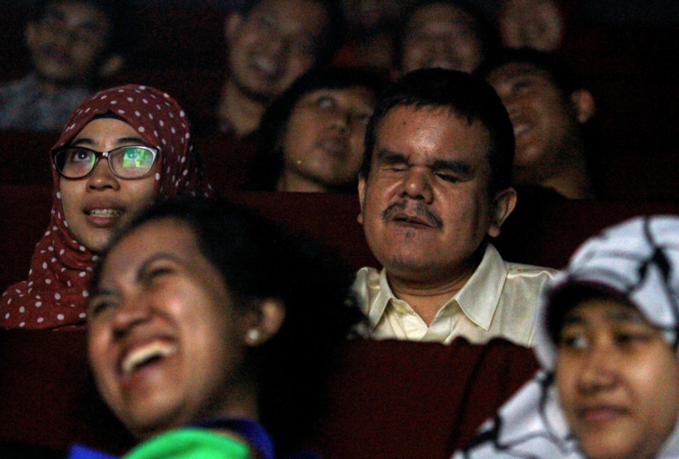 A blind person were watching a movie with his whisperer, which this routine can also called with 'Whisper Theatre' at a small cinema in Jakarta, Indonesia