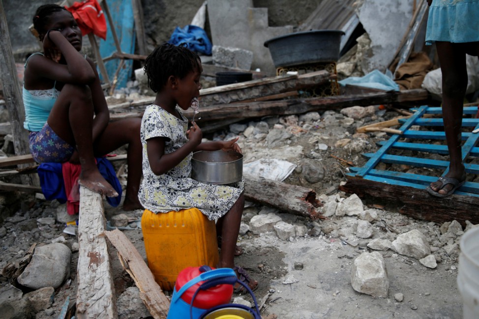 A girl eats at her destroyed house after Hurricane Matthew hit Jeremie
