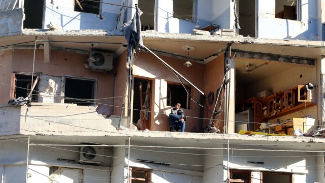 A man sits on the balcony of his damaged house in the rebel held besieged al-Sukkari neighbourhood of Aleppo,