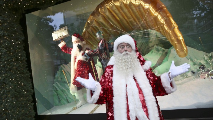 A man in a Santa Claus outfit poses in front of a Christmas window display at a Selfridges store on Oxford Street in London
