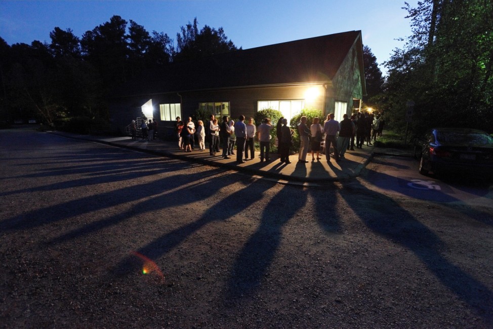Voters cast shadows as they wait in a line at a polling station open into the evening as early voting for the 2016 general elections begins in Durham