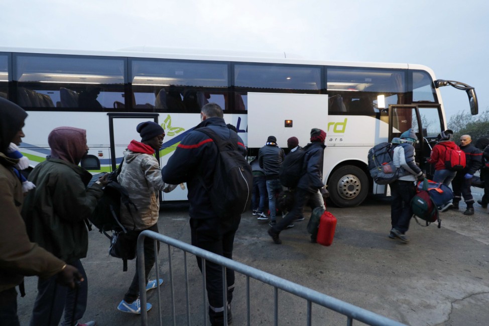Migrants carry their belongings as they board a bus at the start of their evacuation and transfer to reception centers in France, and the dismantlement of the camp called the 'Jungle' in Calais