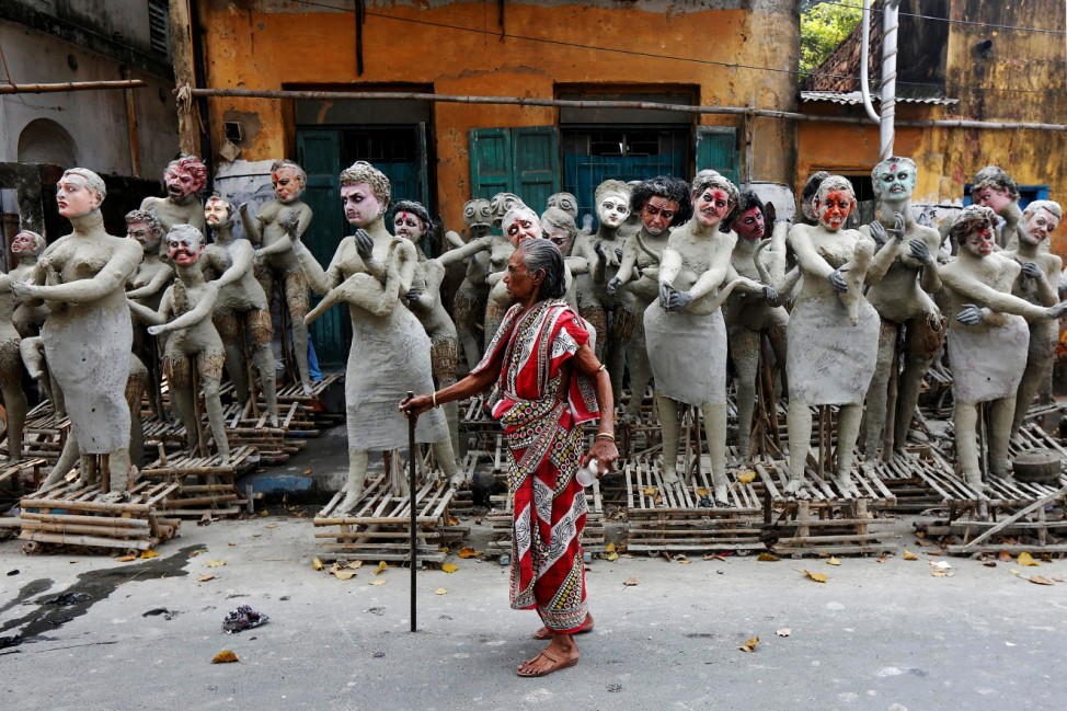 A woman walks past semi-finished clay idols of the Hindu mythological characters 'Dakinis' and 'Yoginis' at a roadside workshop ahead of the Kali Puja festival in Kolkata